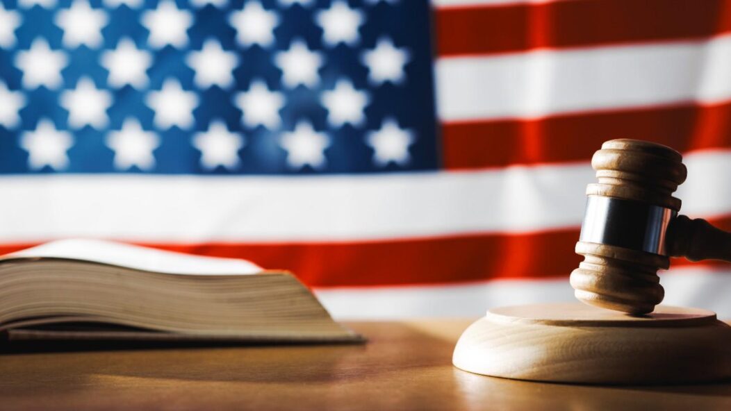 Judge gavel and law book before U.S. flag symbolizing federal vs state immigration law legal conflicts