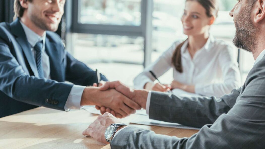 Business professionals handshake during H-1B visa sponsorship meeting – cap-exempt and concurrent H-1B employment opportunities