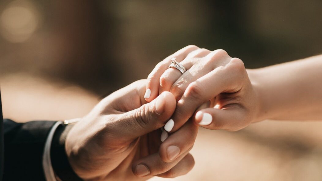 Couple holding hands with wedding ring – marriage-based visa and spousal green card process