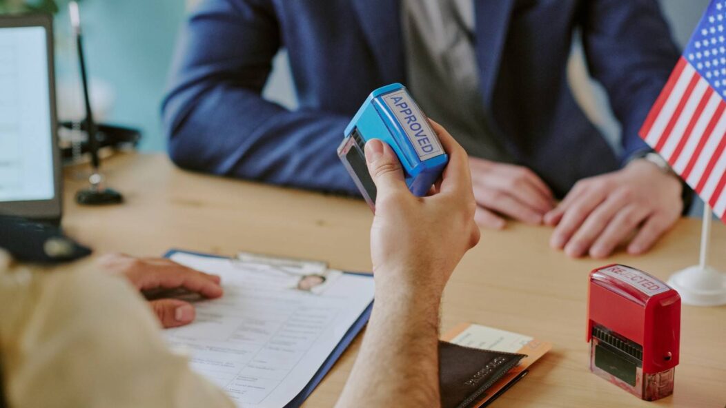 Immigration officer stamping approved visa application for H-1B petition approval and USCIS policy changes