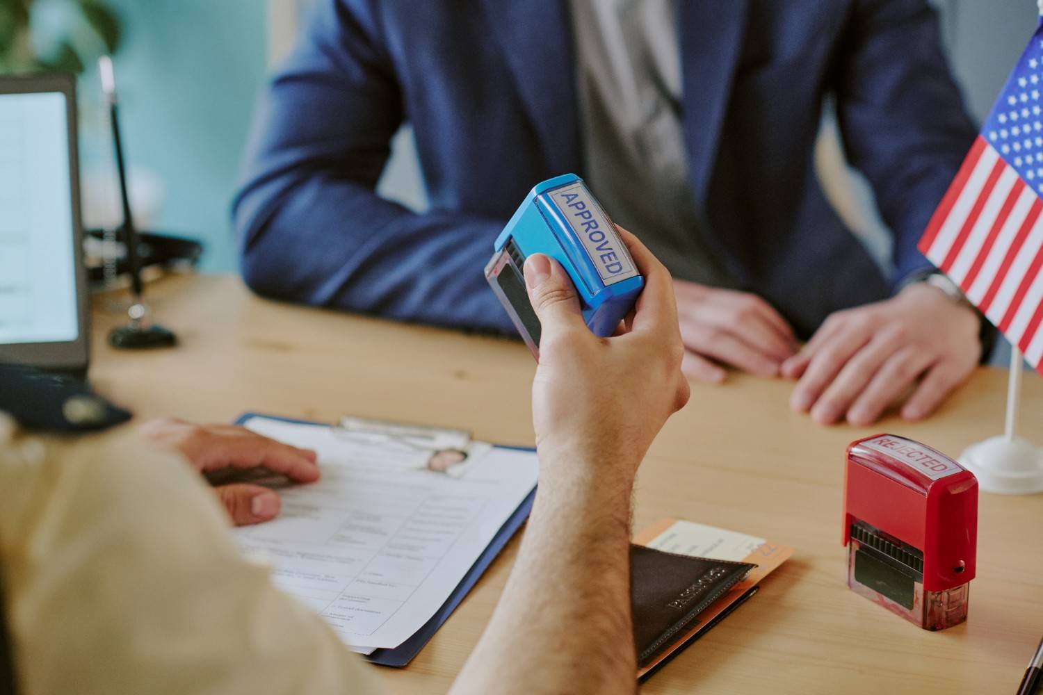 Immigration officer stamping approved visa application for H-1B petition approval and USCIS policy changes