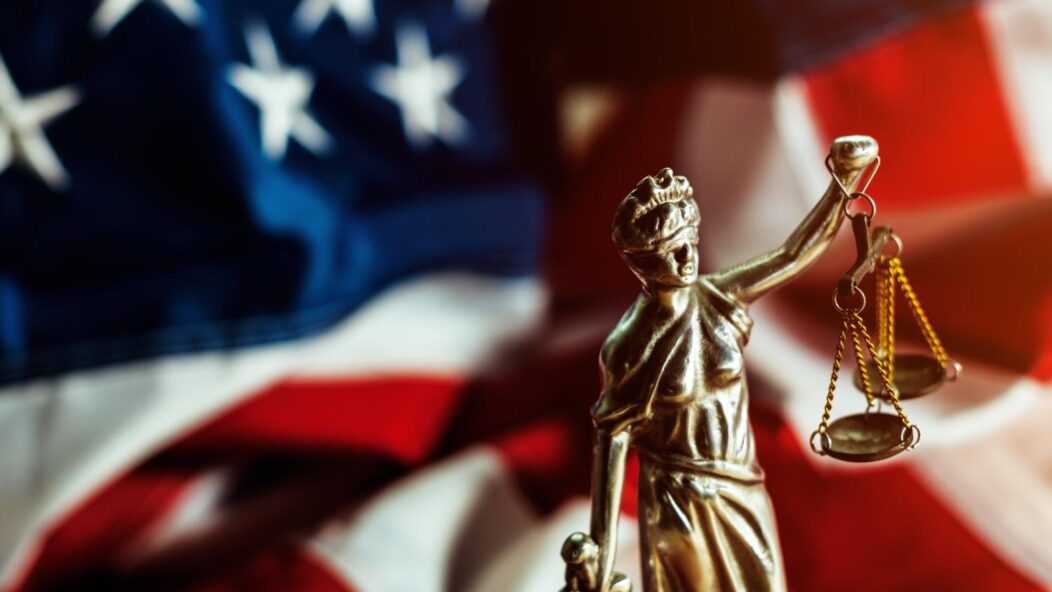 Lady Justice statue with scales in front of U.S. flag symbolizing federal court role in immigration dispute resolution