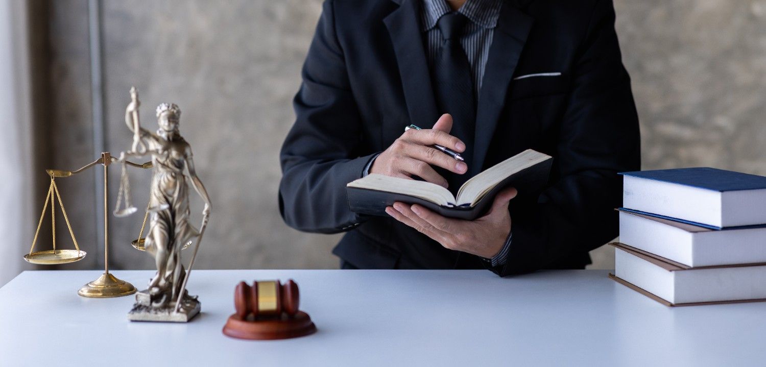 Immigration attorney reviewing legal documents for USCIS RFE and NOID response with Lady Justice statue and law books