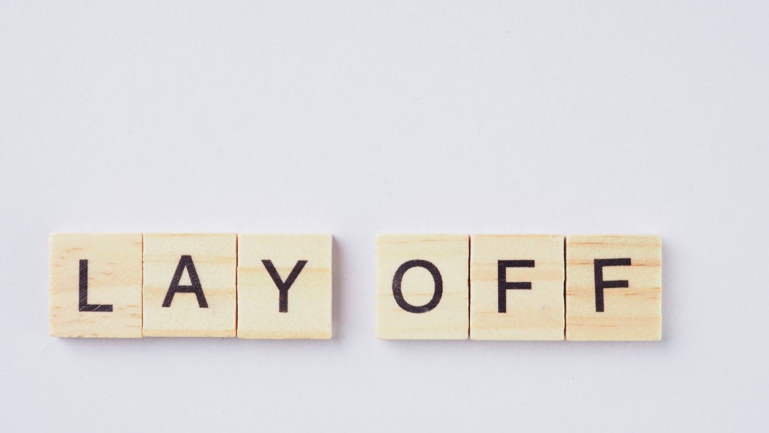 Layoff announcement spelled on wooden blocks representing tech industry job cuts