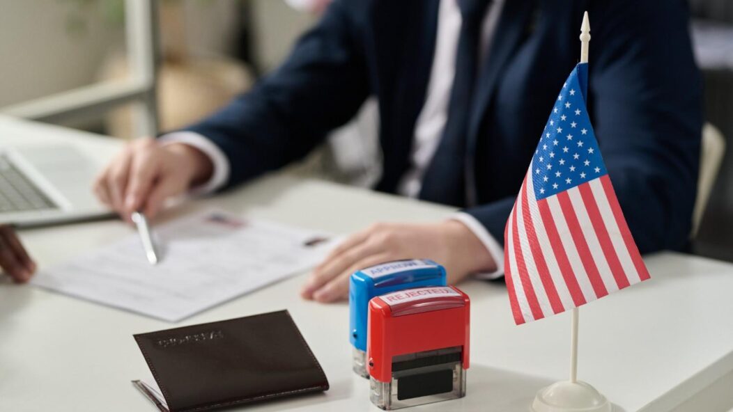 USCIS officer reviewing H-1B visa documents with approved and rejected stamps during worksite compliance visit