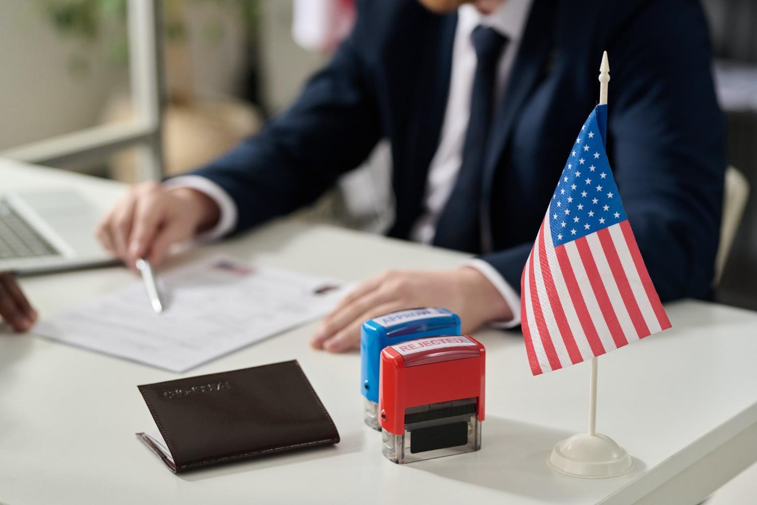 USCIS officer reviewing H-1B visa documents with approved and rejected stamps during worksite compliance visit