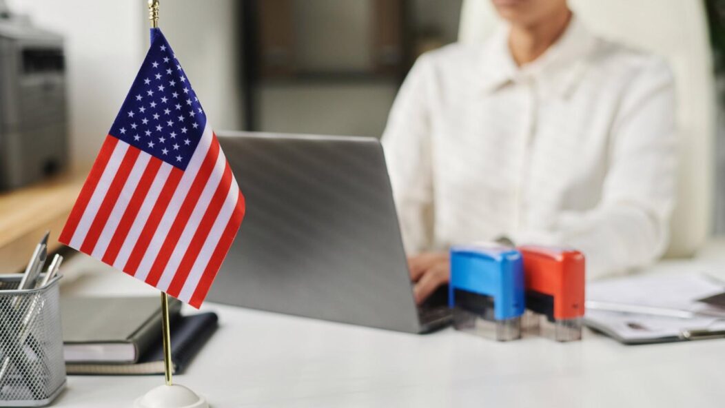 U.S. flag on desk at visa office representing H-1B revocation and NOIR immigration process