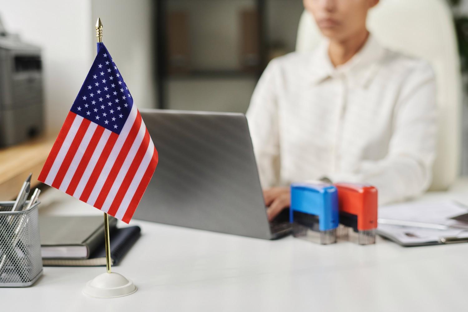 U.S. flag on desk at visa office representing H-1B revocation and NOIR immigration process
