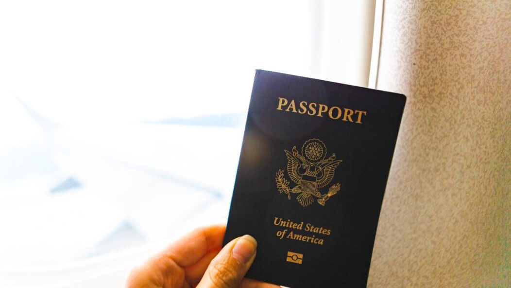 An immigration officer reviewing a passport and travel documents at an airport desk, highlighting the process of visa verification.