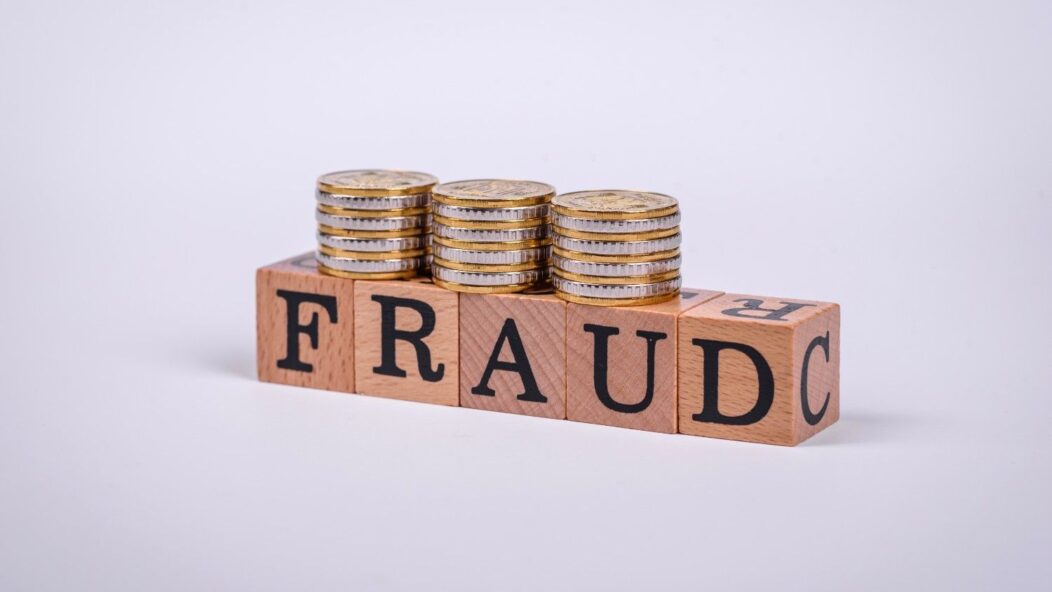 H-1B visa fraud concept with a man in handcuffs holding a credit card in front of a laptop, symbolizing illegal practices and consequences.