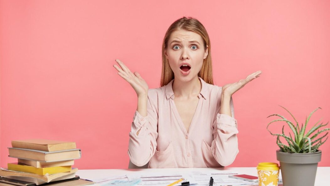 Concerned woman holding a toy airplane, seated at a desk with maps, laptop, and notebooks, representing visa application challenges.