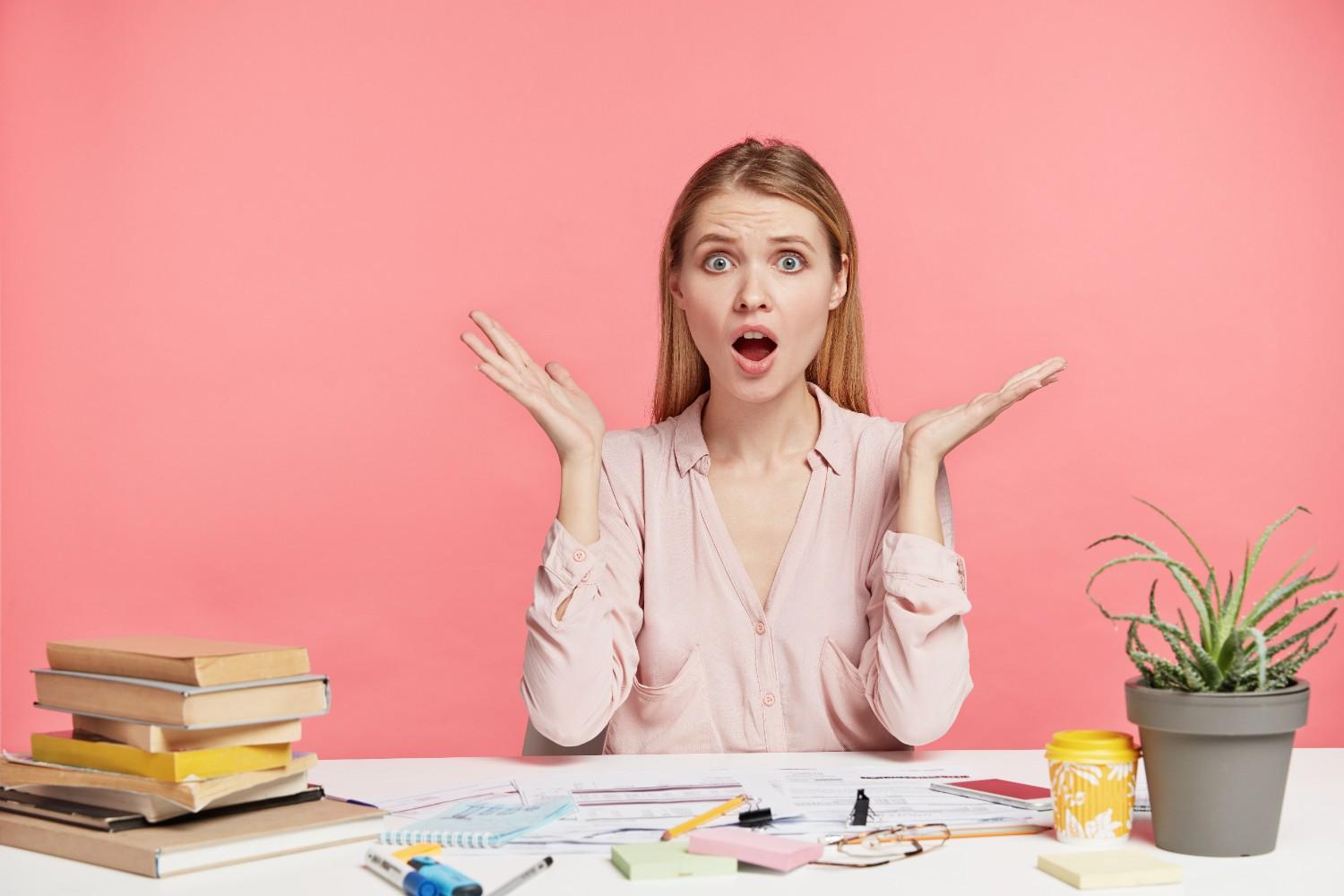 Concerned woman holding a toy airplane, seated at a desk with maps, laptop, and notebooks, representing visa application challenges.