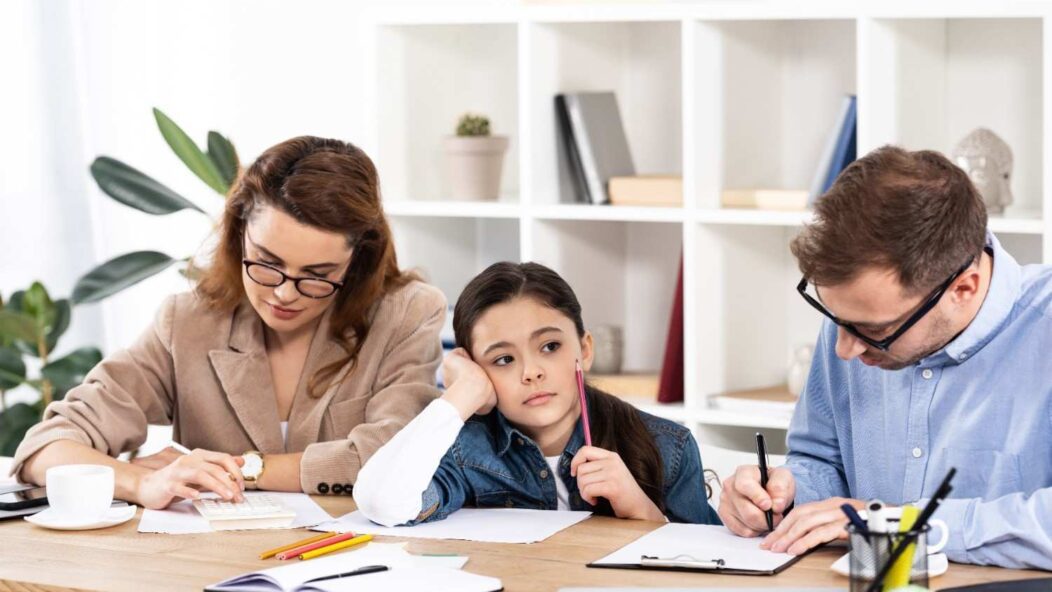 A family discussing citizenship documents with their child in a bright, modern office. The parents and child are smiling and engaged.