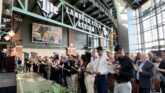 Immigrants taking the Oath of Allegiance during a naturalization ceremony in a large atrium, symbolizing the path to U.S. citizenship.