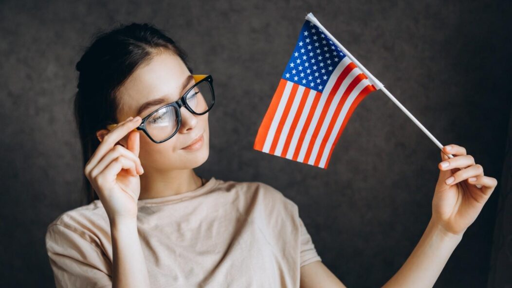 Thoughtful young woman holding a small American flag, symbolizing immigration assistance and navigating USCIS case challenges.