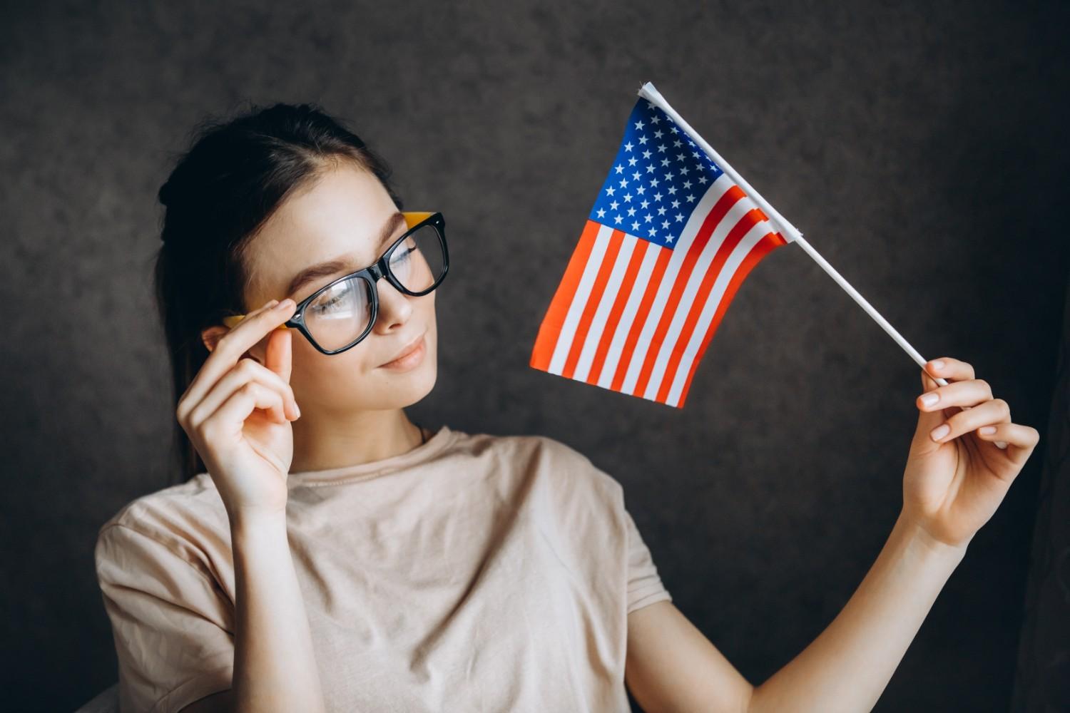 Thoughtful young woman holding a small American flag, symbolizing immigration assistance and navigating USCIS case challenges.