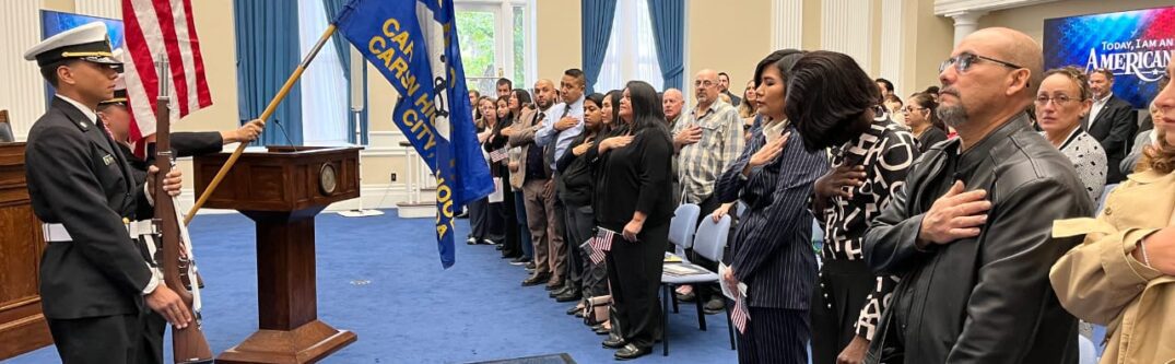 USCIS naturalization ceremony in Nevada, featuring attendees pledging allegiance with flags displayed, symbolizing U.S. citizenship process.