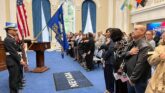 USCIS naturalization ceremony in Nevada, featuring attendees pledging allegiance with flags displayed, symbolizing U.S. citizenship process.