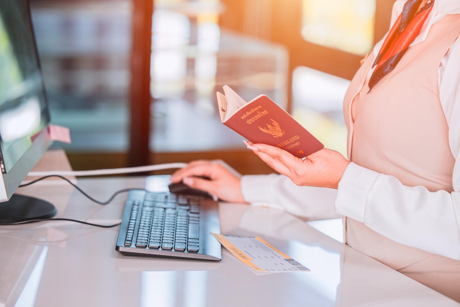 An immigration officer reviewing a passport and travel documents at an airport desk, highlighting the process of visa verification.