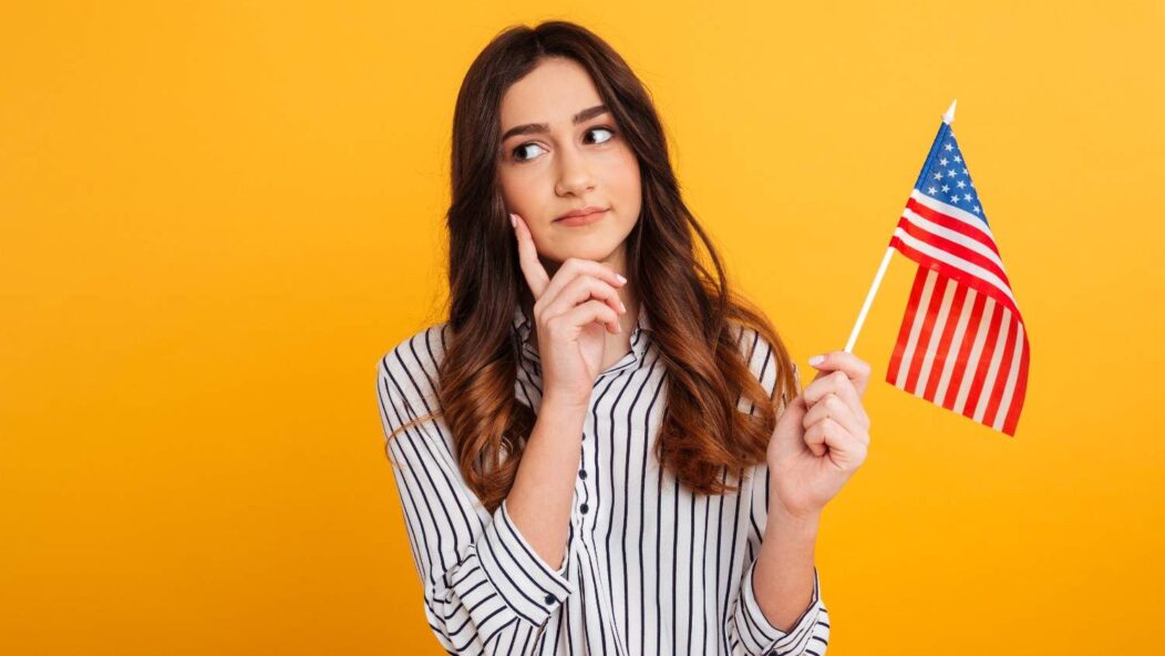 Thoughtful young woman holding a small American flag, symbolizing immigration assistance and navigating USCIS case challenges.