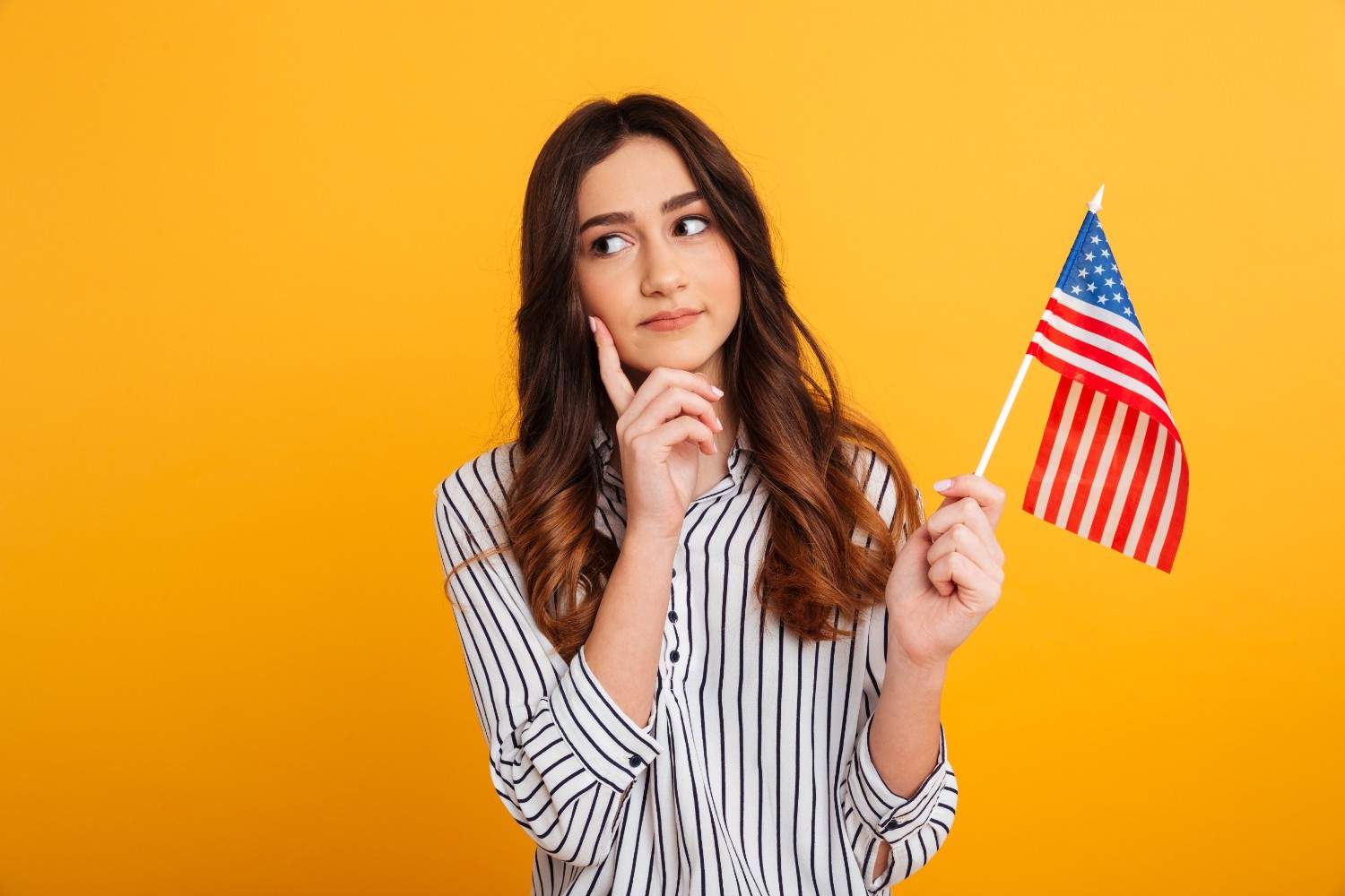 Thoughtful young woman holding a small American flag, symbolizing immigration assistance and navigating USCIS case challenges.