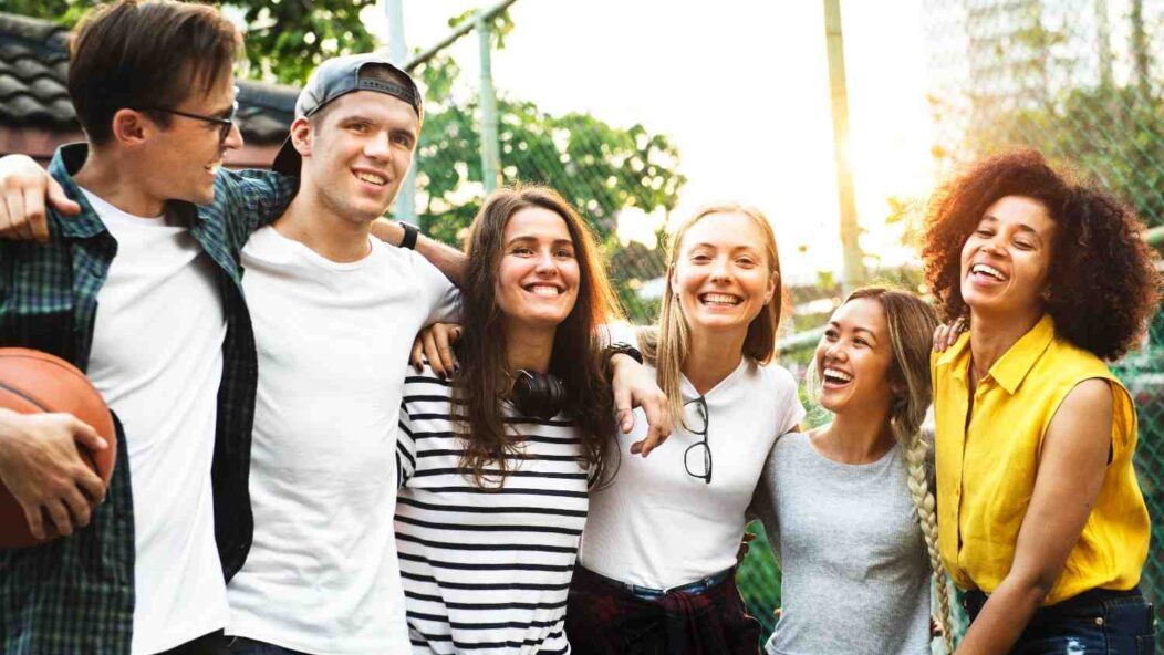 A diverse group of young adults smiling and bonding outdoors, symbolizing inclusivity, connection, and shared experiences.