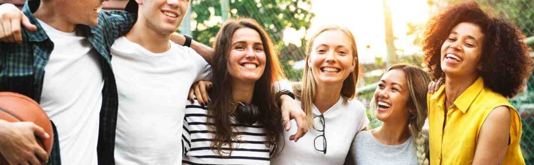 A diverse group of young adults smiling and bonding outdoors, symbolizing inclusivity, connection, and shared experiences.