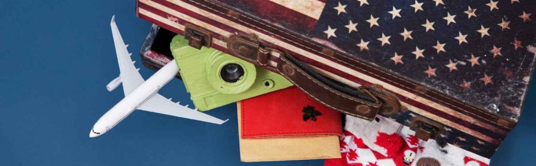 A suitcase featuring the American flag, with items like a toy airplane, a green camera, a red passport, and holiday socks sticking out, symbolizing travel, immigration, and holiday spirit.