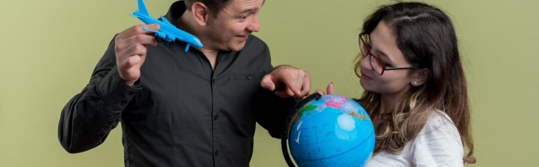 Man holding a toy airplane pointing at a globe with a woman, symbolizing global opportunities for J-1 visa holders.