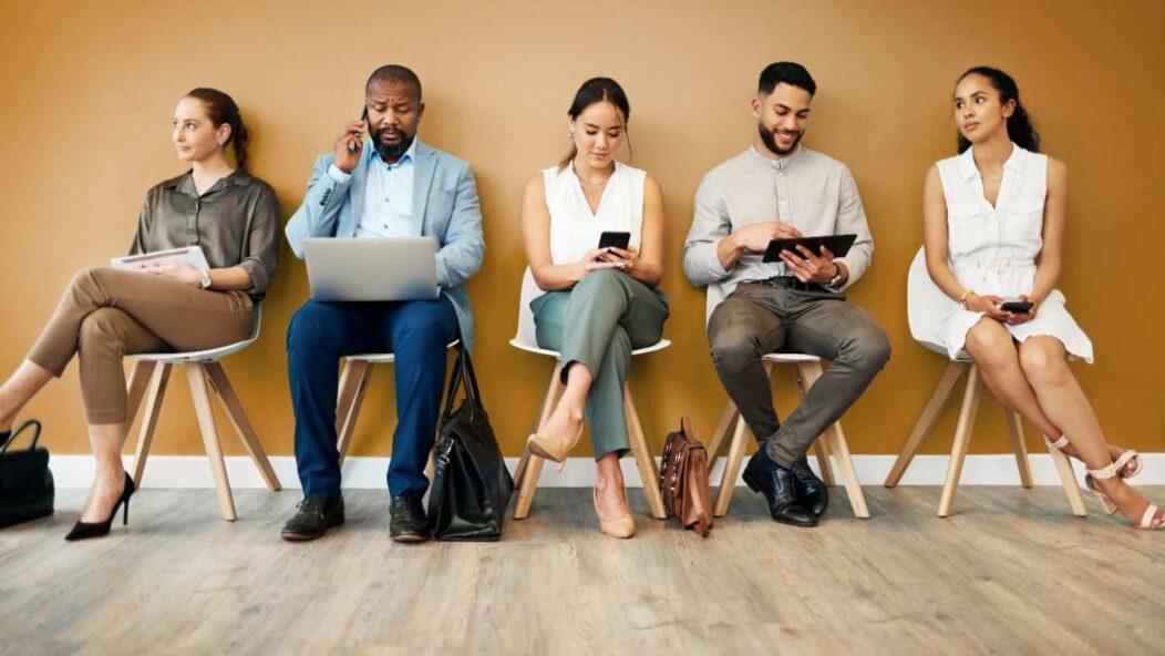 Professional workers in line for job opportunities with the words 'We Want You!' and a briefcase icon highlighting career recruitment.