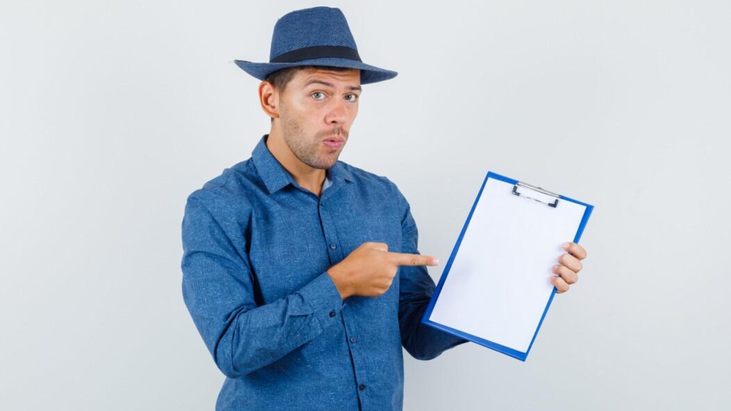 Man pointing to a blank clipboard, symbolizing the importance of filling Form I-129 correctly for USCIS compliance.