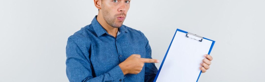 Man pointing to a blank clipboard, symbolizing the importance of filling Form I-129 correctly for USCIS compliance.