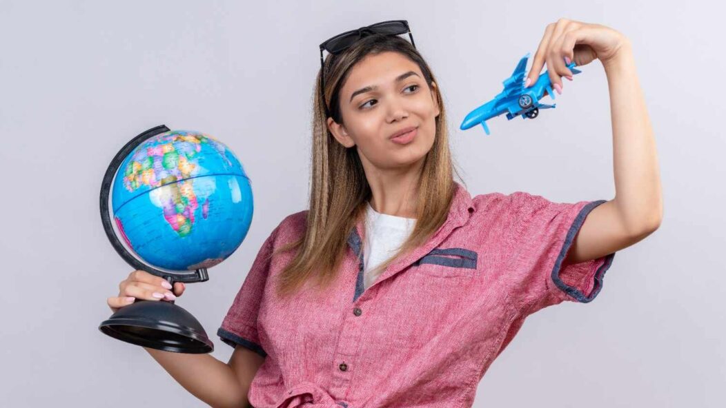 A young woman holding a globe in one hand and a toy airplane in the other, symbolizing travel and opportunities across the world.