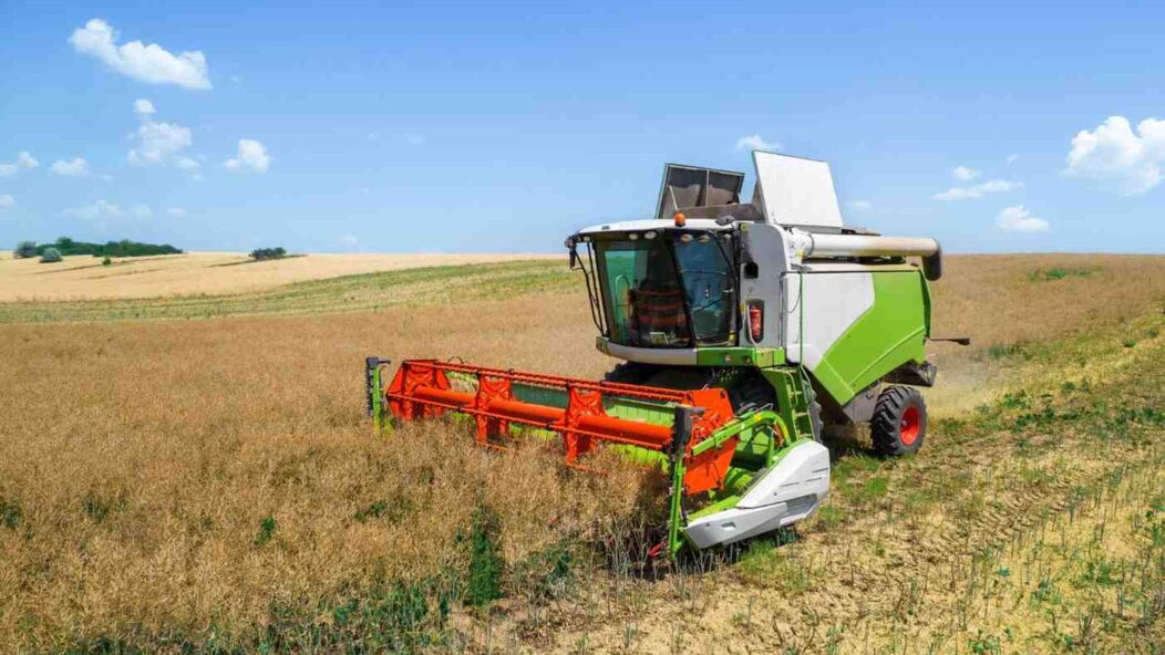 A modern combine harvester working on a vast farmland, representing opportunities for immigrant farmers in the U.S.