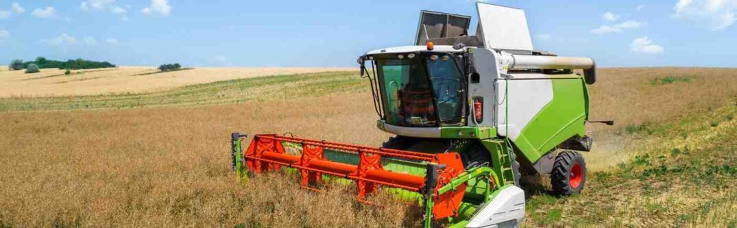 A modern combine harvester working on a vast farmland, representing opportunities for immigrant farmers in the U.S.