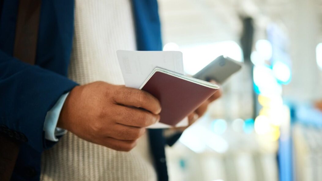 Man in a red sweater and mask holding documents, symbolizing the importance of visa compliance and documentation for U.S. work visas.