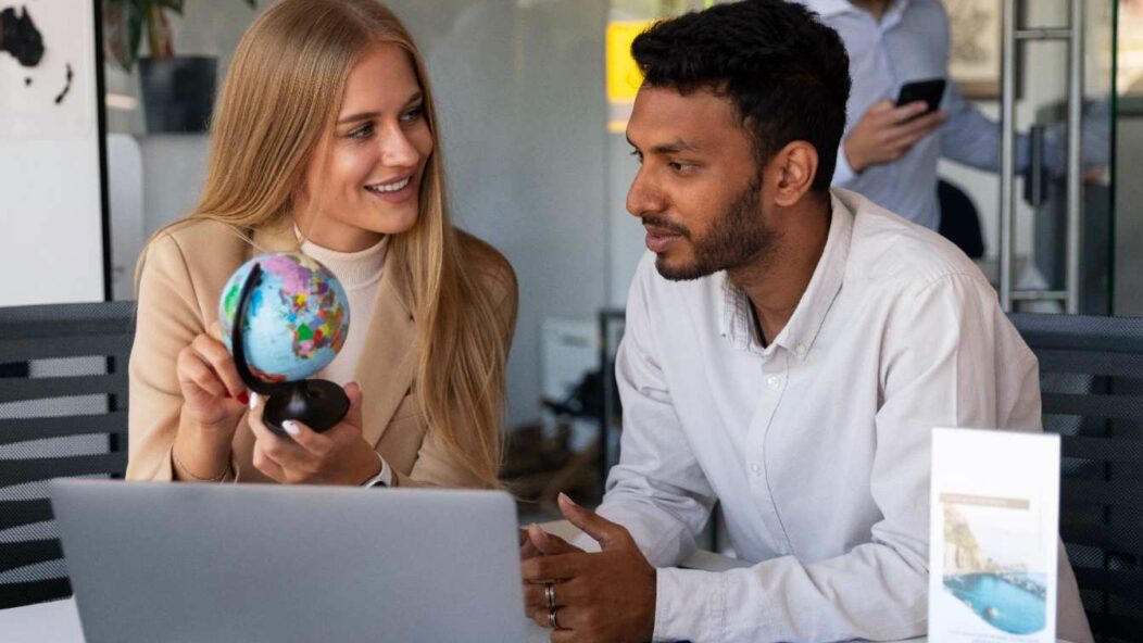 Employer discussing H-2B visa options with a foreign worker while pointing at a globe, symbolizing international workforce solutions.