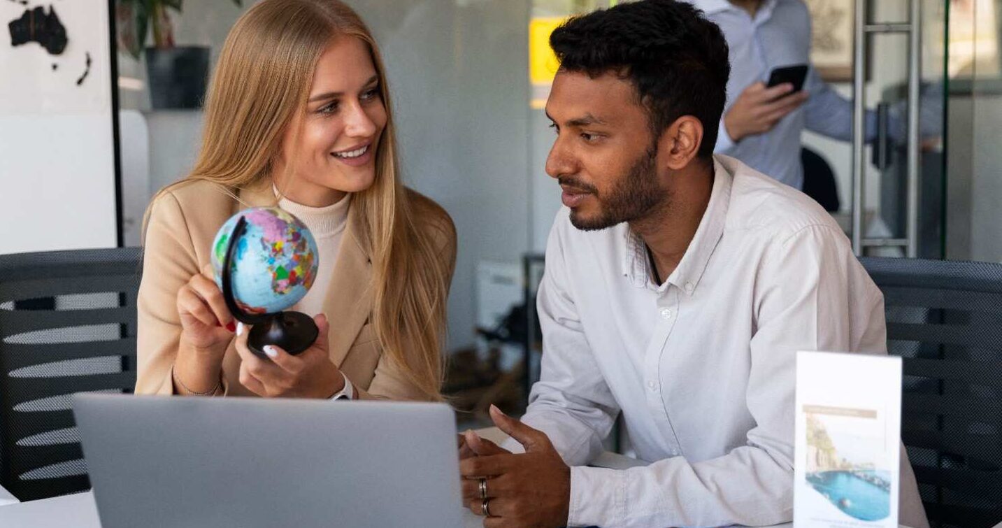 Employer discussing H-2B visa options with a foreign worker while pointing at a globe, symbolizing international workforce solutions.