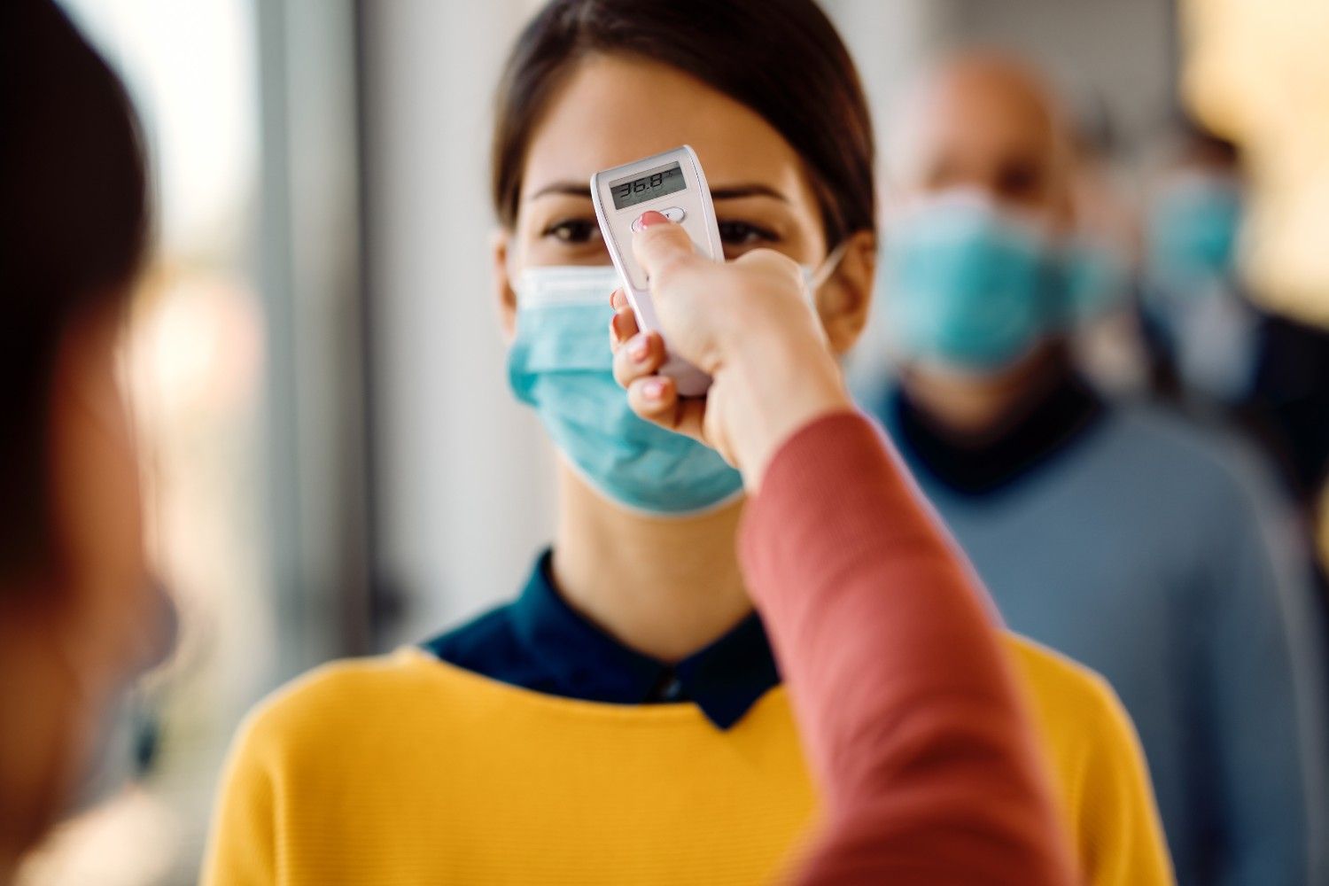Person wearing a mask undergoing a temperature check during COVID-19 protocols