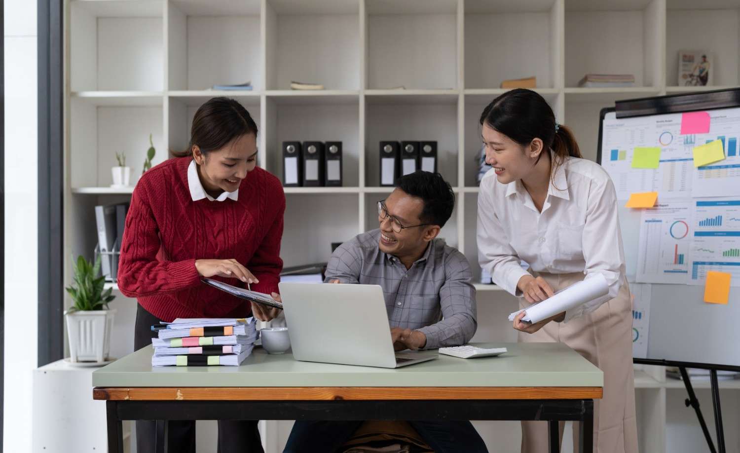 International students discussing self-employment opportunities on OPT with laptops and documents in a modern workspace.