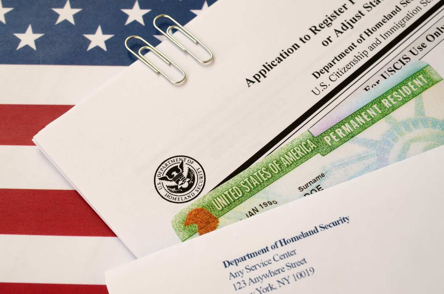 Person reviewing a U.S. permanent resident card and application form on a desk.