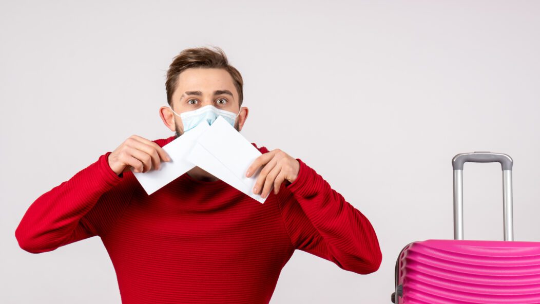 Man in a red sweater and mask holding documents, symbolizing the importance of visa compliance and documentation for U.S. work visas.