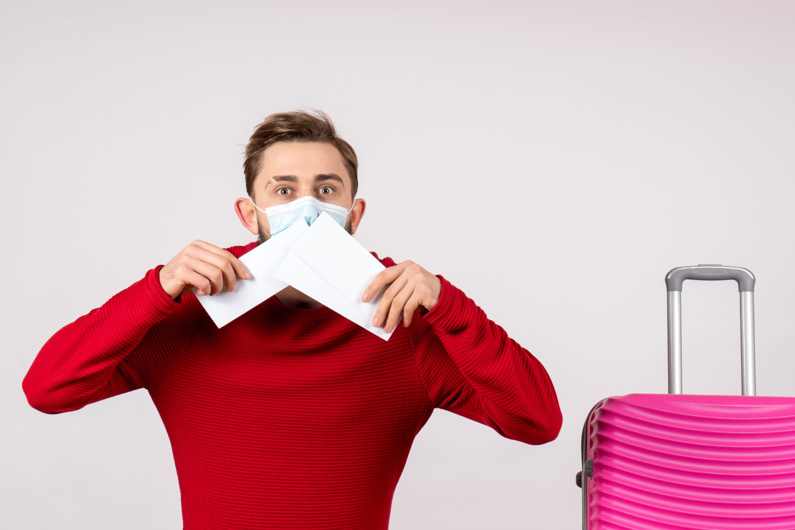 Man in a red sweater and mask holding documents, symbolizing the importance of visa compliance and documentation for U.S. work visas.