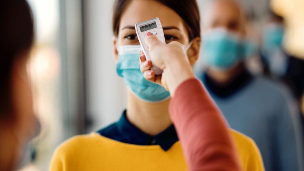 Person wearing a mask undergoing a temperature check during COVID-19 protocols