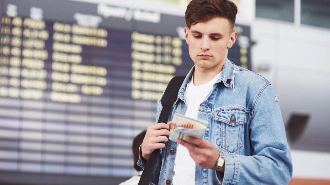 Man at airport looking at his flight ticket, reflecting on USCIS delays and how legal action can expedite decisions.