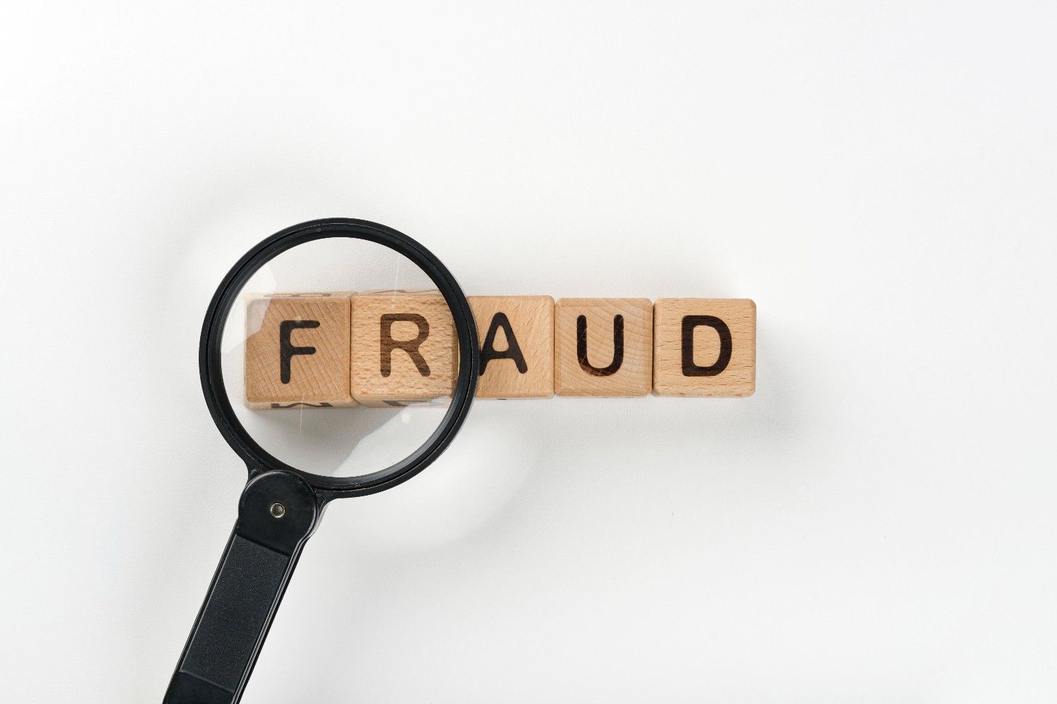 Magnifying glass focusing on the word 'FRAUD' representing H1B visa fraud litigation and revocation issues