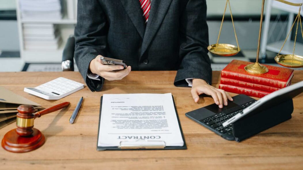 Immigration attorney discussing H-1B visa revocation legal remedies with a client, holding a contract and pen, symbolizing legal counsel and professional guidance.