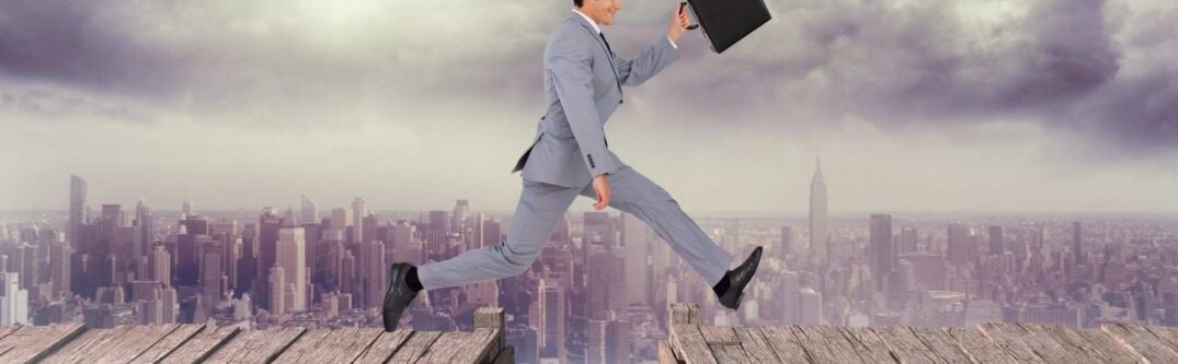 Businessman jumping across a broken bridge over a city skyline, symbolizing overcoming L-1A visa denial challenges and navigating the appeal process.