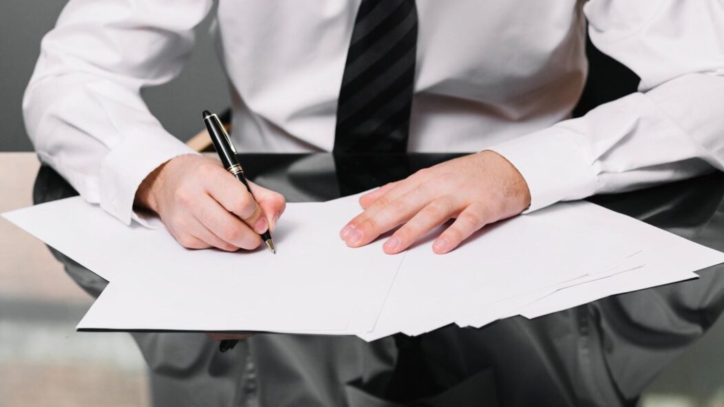 A professional in a suit signing official immigration documents, representing legal solutions for STEM OPT and H1B visa fraud implications.