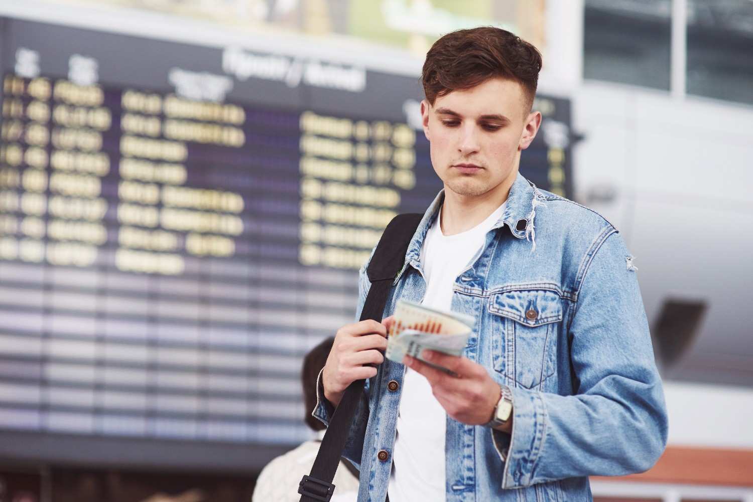 Man at airport looking at his flight ticket, reflecting on USCIS delays and how legal action can expedite decisions.